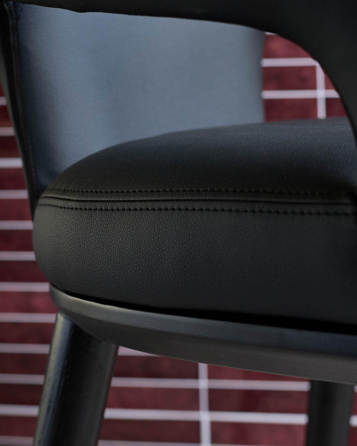 Close-up of a stylish black leather chair with a sleek frame, showcasing comfort and modern design.