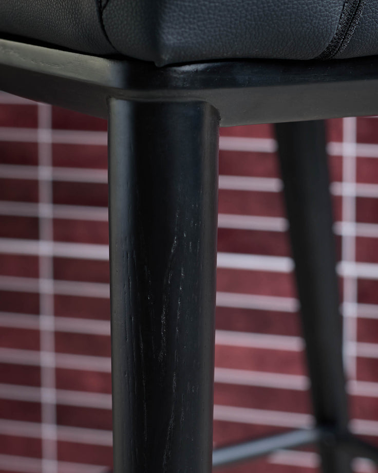 Close-up of a black bar stool leg, showing the textured finish and construction details. Stylish seating for your kitchen.