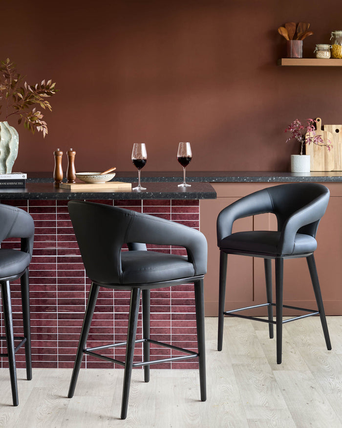 Stylish black bar stools with curved backs and armrests, perfect for a modern kitchen or bar area.