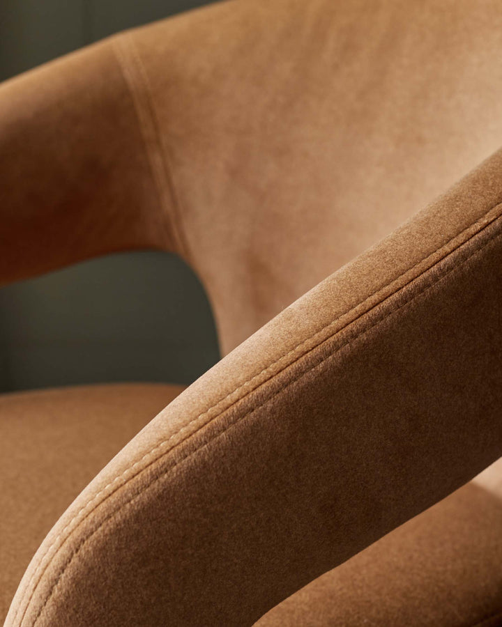 Close-up of a stylish armchair with a textured, brown upholstery, showcasing the curved armrest and stitched detailing.