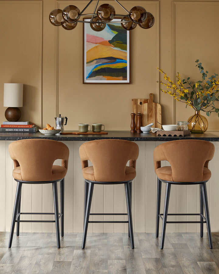 Three stylish upholstered bar stools with dark frames sit under a sleek counter, complemented by contemporary decor.