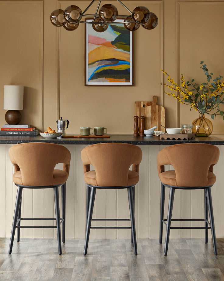 Three stylish upholstered bar stools with dark frames sit under a sleek counter, complemented by contemporary decor.
