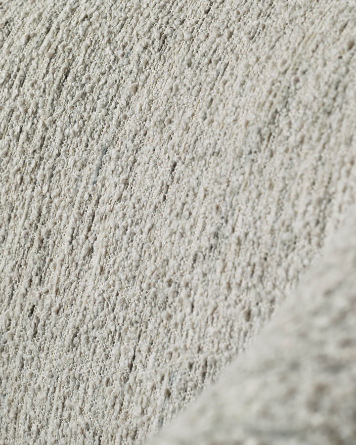Close-up of a textured, neutral-toned fabric, possibly upholstery for furniture.