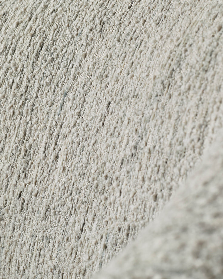Close-up of a textured, neutral-toned fabric, possibly upholstery for furniture.