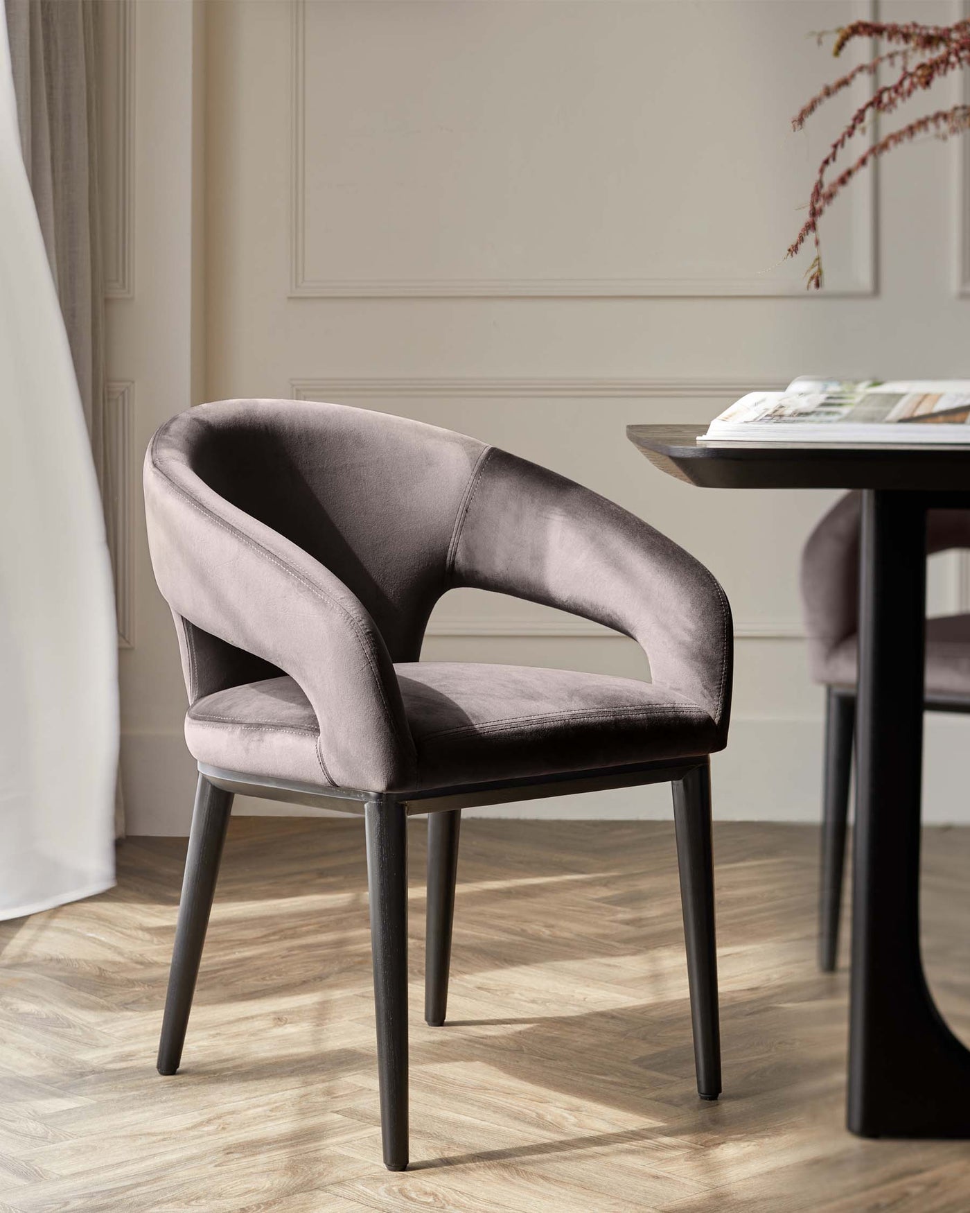 Elegant modern dining chair with a curved backrest and plush mauve velvet upholstery, featuring a sleek black frame with four straight legs.