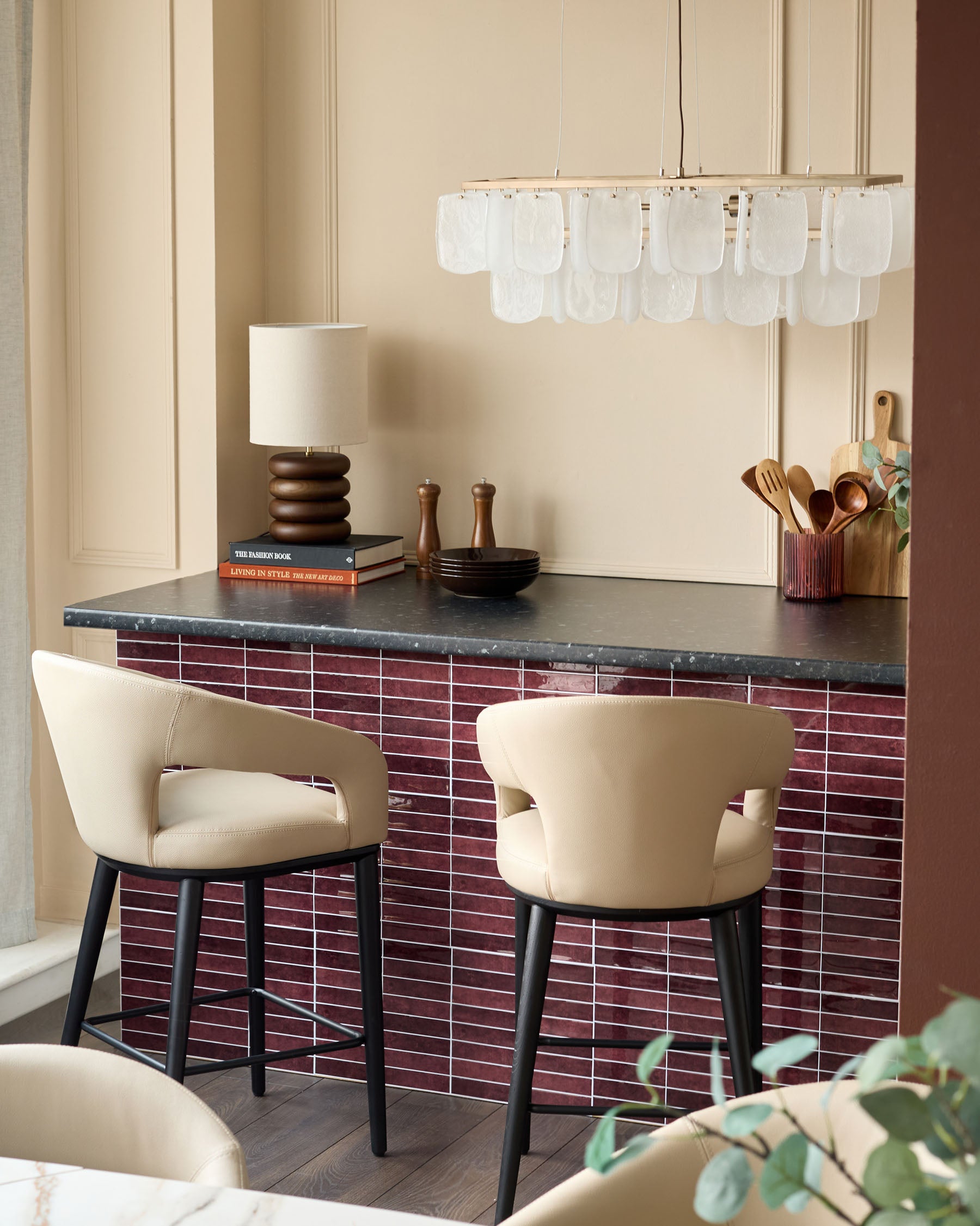 Stylish kitchen island with modern stools, elegant lamp, and unique chandelier, creating a chic and inviting atmosphere.