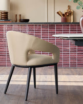 A stylish beige chair with black legs sits beside a modern table, set against a backdrop of chic kitchen decor.