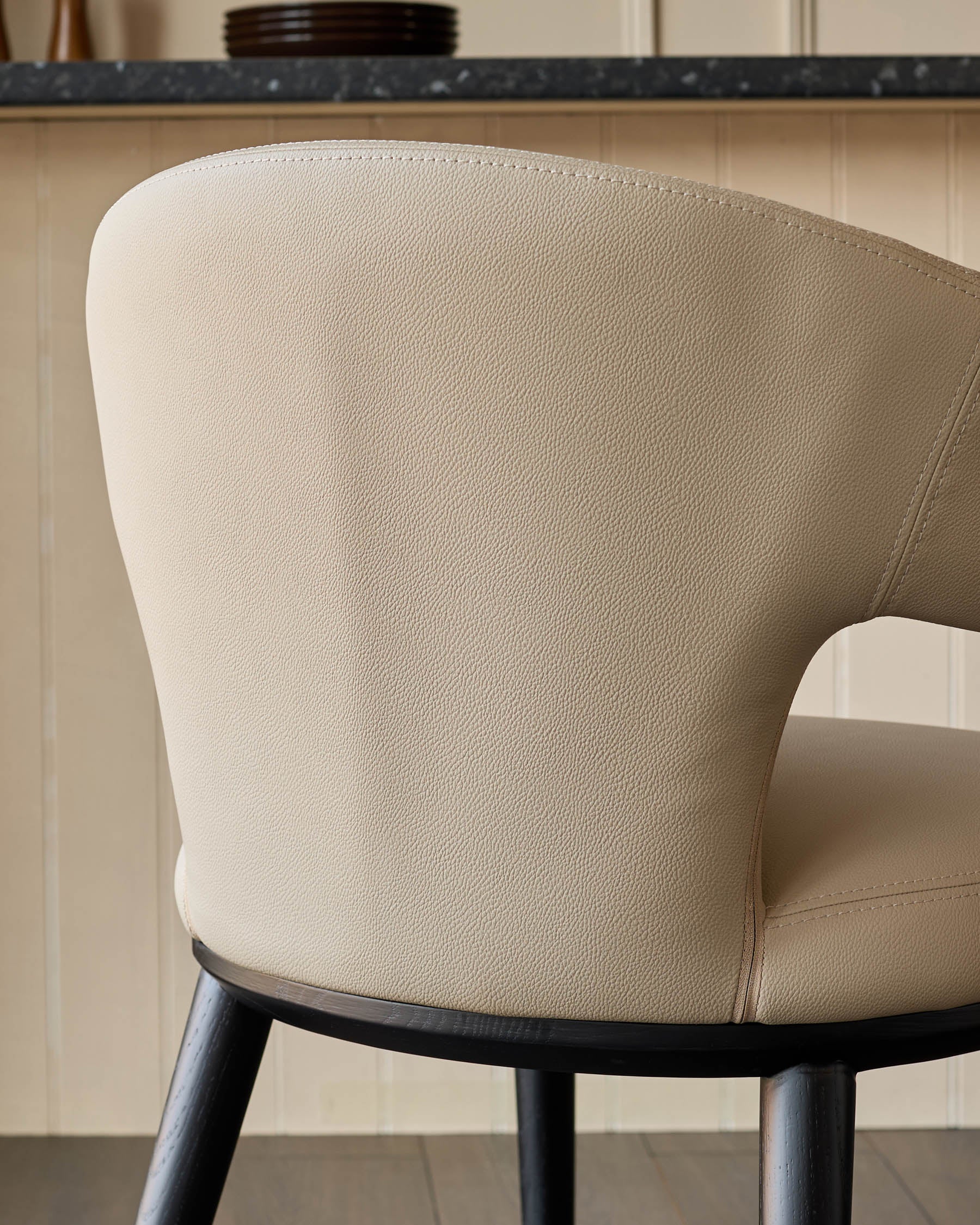 Close-up of a stylish beige upholstered chair with dark wood legs, showcasing its quality and design.