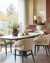 Dining room set with marble table and six upholstered chairs. Modern design with warm neutrals and natural light.