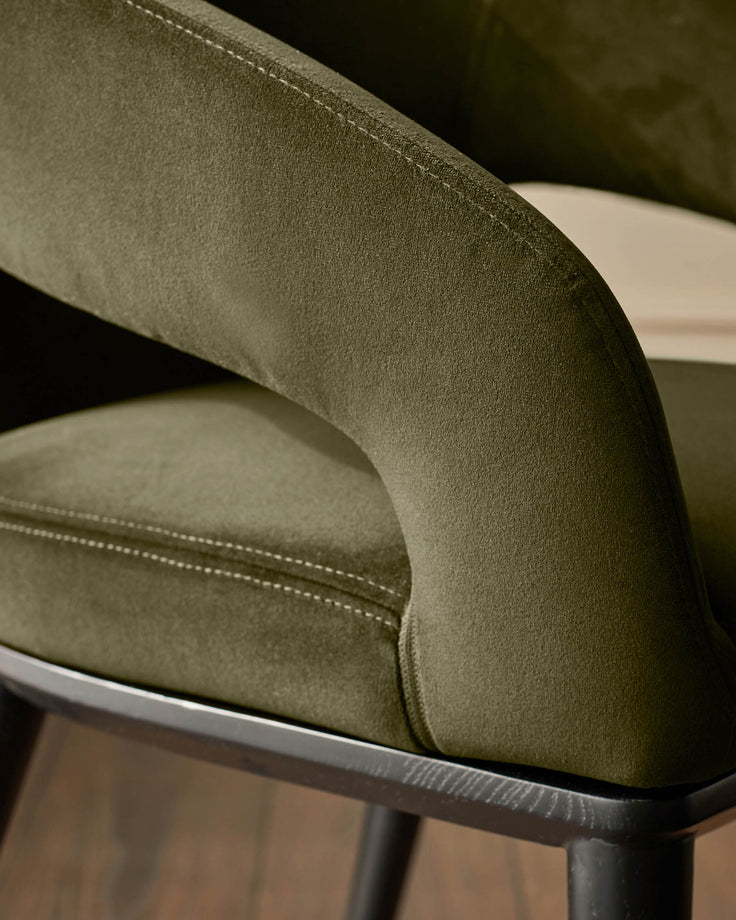 Close-up of a stylish olive green chair, showcasing its plush fabric and sleek dark wooden frame.