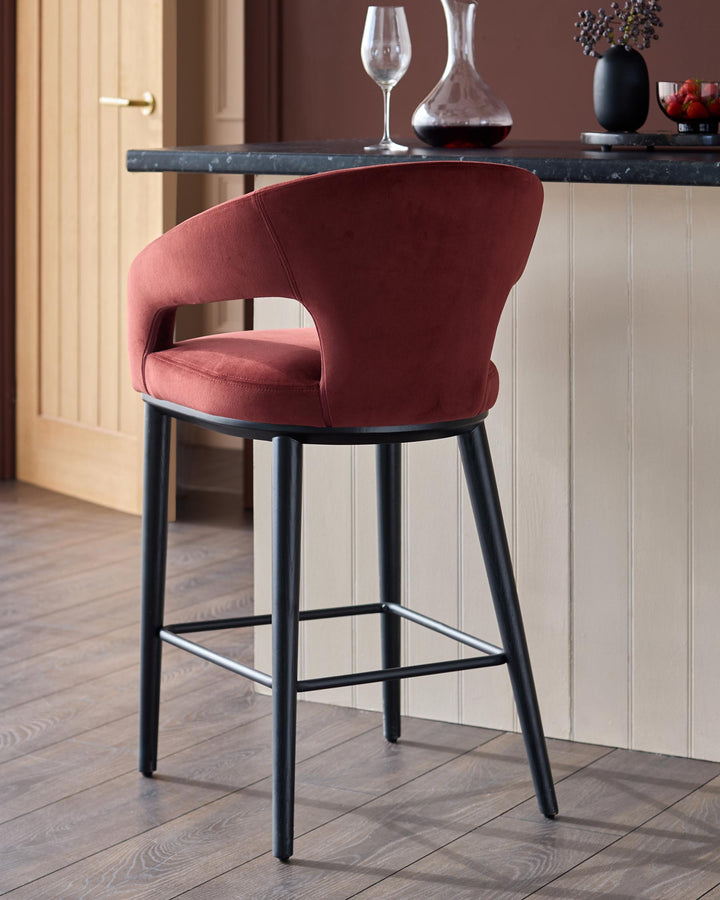 A plush red bar stool with a curved back and dark wooden legs, positioned in a stylish kitchen setting.