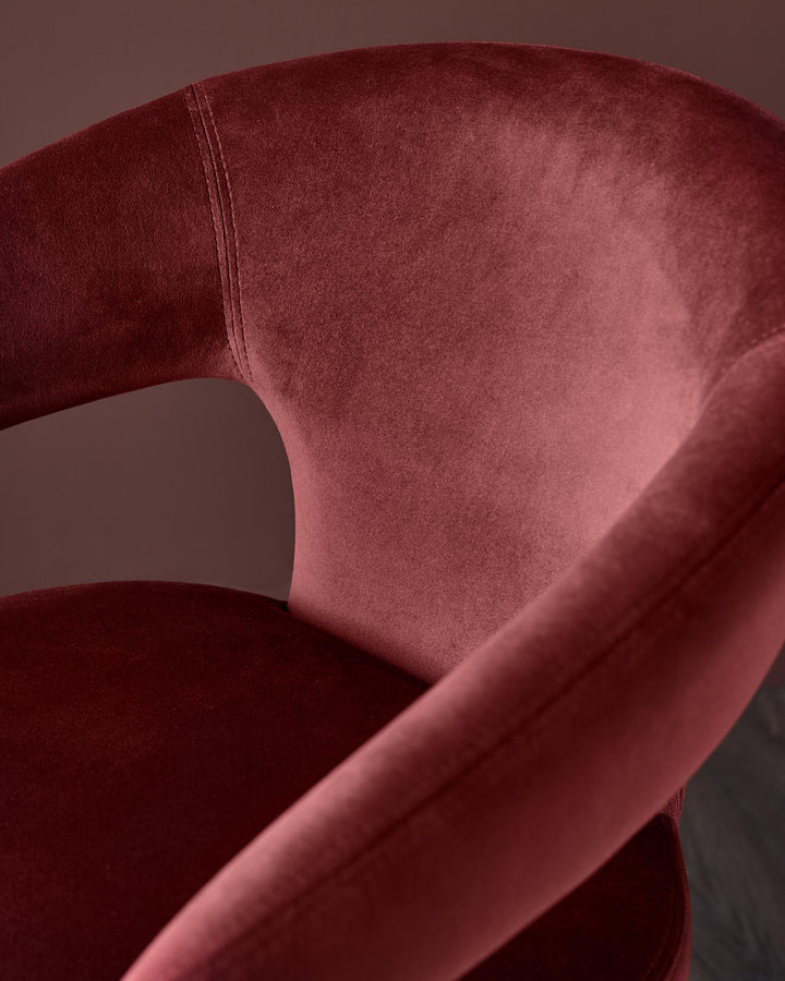 Close-up of a luxurious, dusky pink velvet chair with curved back and arm rests. Stylish and comfortable seating option.