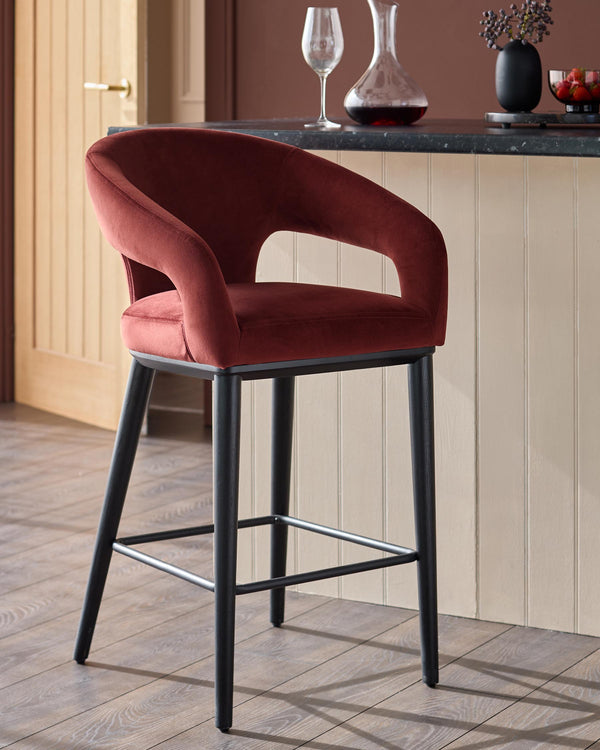 A stylish rust coloured velvet bar stool with black legs, set in a modern kitchen setting.