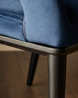 Close-up of a stylish blue chair with dark wood trim and legs, showcasing modern design and comfort.