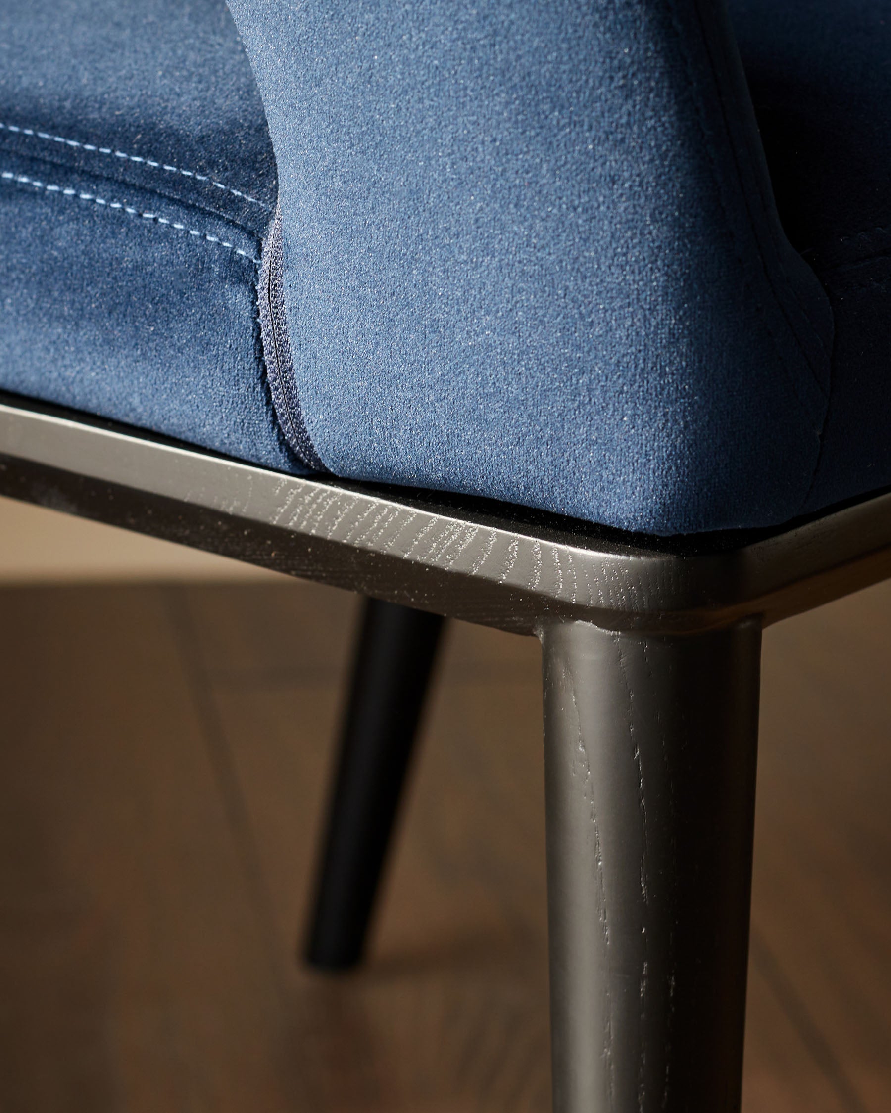 Close-up of a stylish blue chair with dark wood trim and legs, showcasing modern design and comfort.