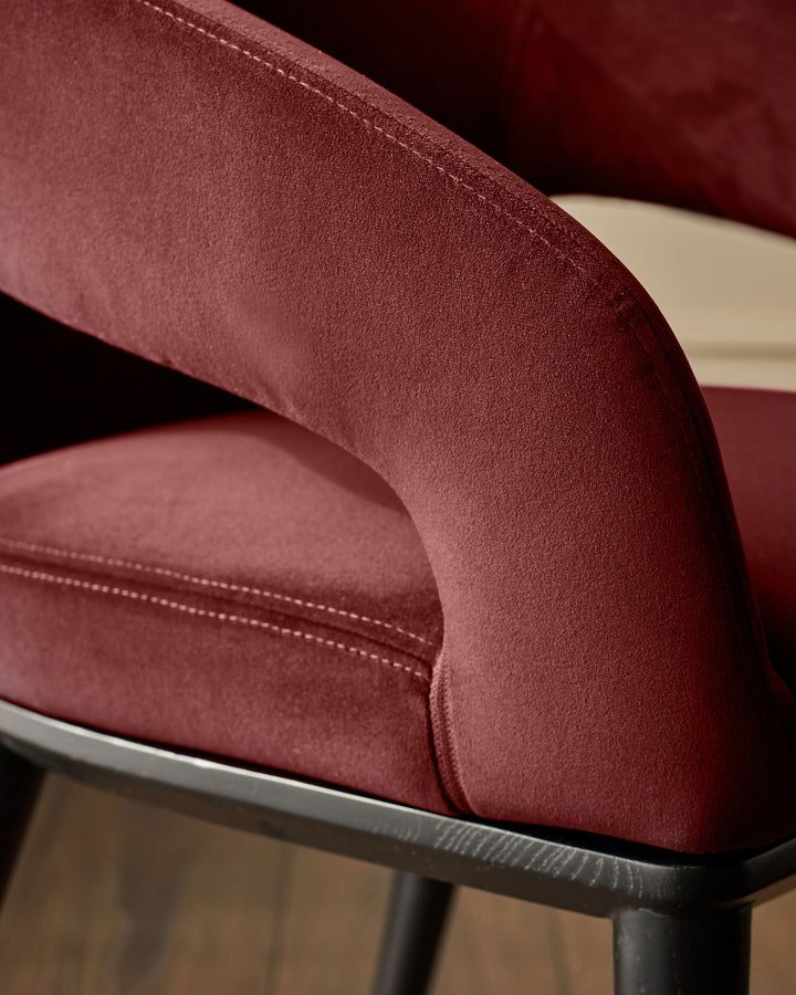 Close-up of a red, upholstered chair with a black frame, showcasing its texture and detailing.
