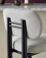 Henley bar stool in ivory fabric with black wooden frame and backrest, angled side view.