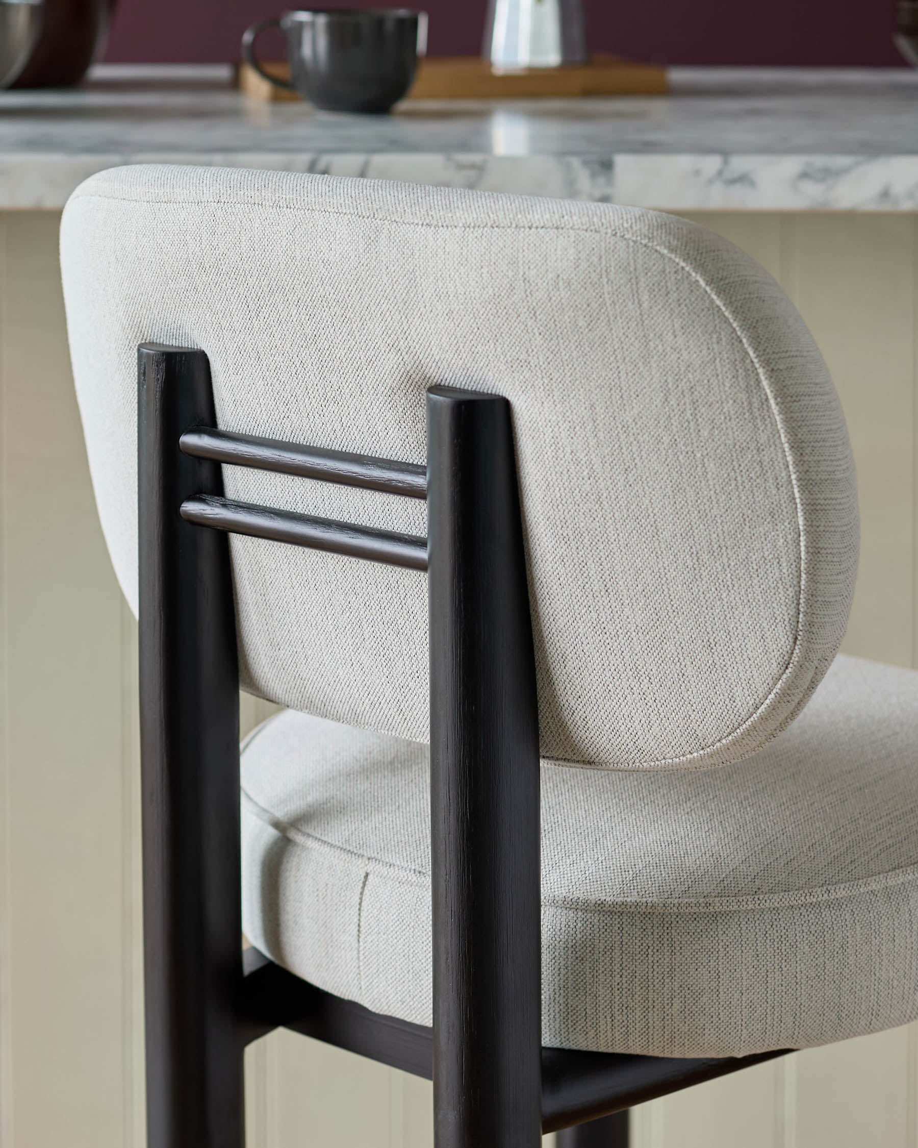 Henley bar stool in ivory fabric with black wooden frame and backrest, angled side view.