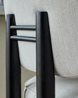 Black wood bar stool with ivory fabric seat, close-up of armrest and backrest detail.