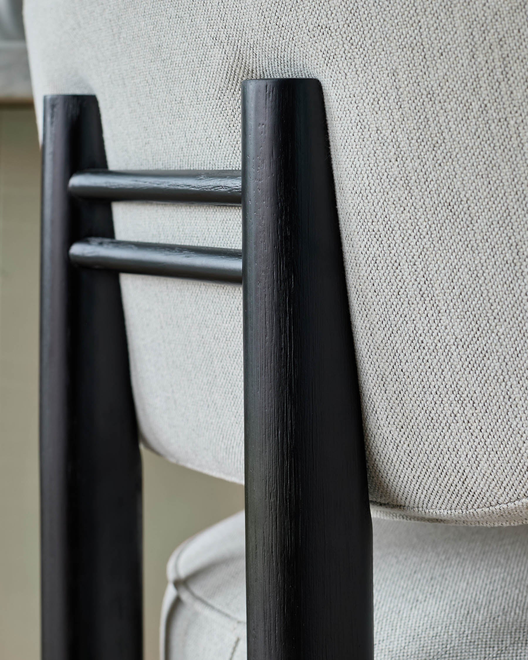 Black wood bar stool with ivory fabric seat, close-up of armrest and backrest detail.