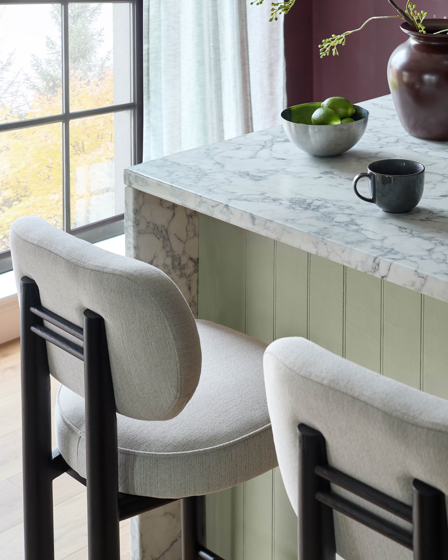 Henley Blackwood bar stool in ivory fabric, shown at marble counter with black frame and rounded backrest.