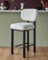 Henley bar stool with ivory fabric seat and backrest, black wooden frame and footrest on wooden flooring.