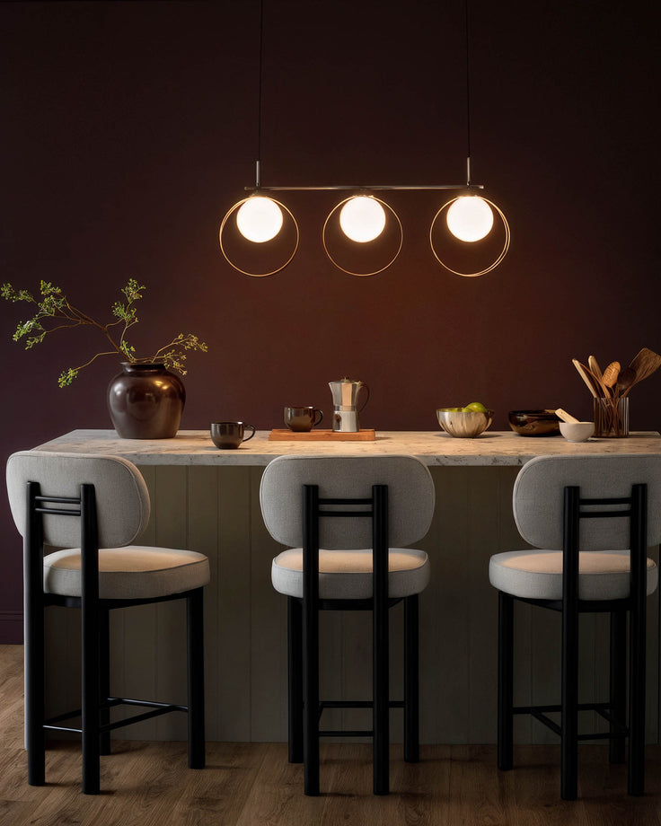 Chloe 3-pendant light with glass shades and silver chrome finish, suspended above a kitchen counter with bar seating.
