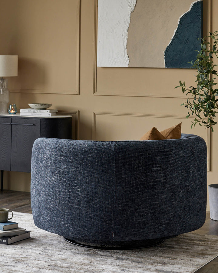 A stylish blue swivel chair, accented with brown scatter cushions, sits on a patterned rug. A cabinet stands nearby.