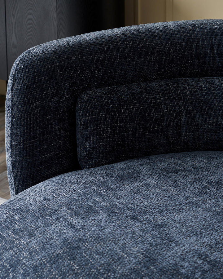 A close-up of a blue textured chair with a rounded back and lumbar support, showing the fabric's weave and texture.