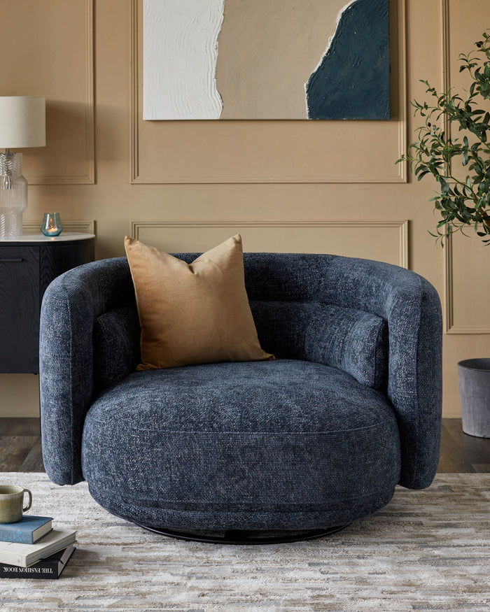A comfy blue swivel chair with a tan cushion sits on a patterned rug, beside a dark cabinet and wall art.