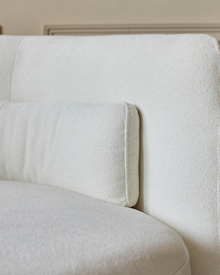 Close up of a modern, light-coloured sofa, showcasing its textured fabric and cushion design.