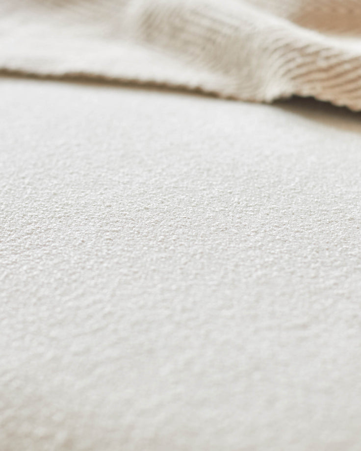 Close-up of neutral textured fabric, possibly upholstery on furniture like a sofa or armchair. Focus on texture and light tones.