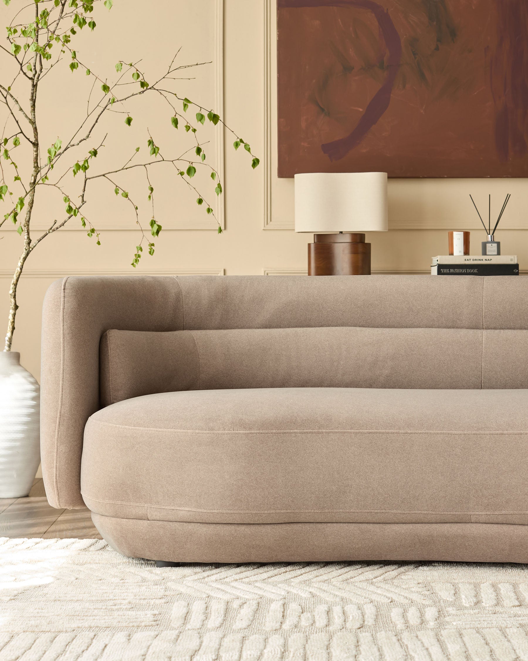 Henry 3-seater sofa in mocha fabric with curved, rounded arms and base, displayed in a styled living room setting.