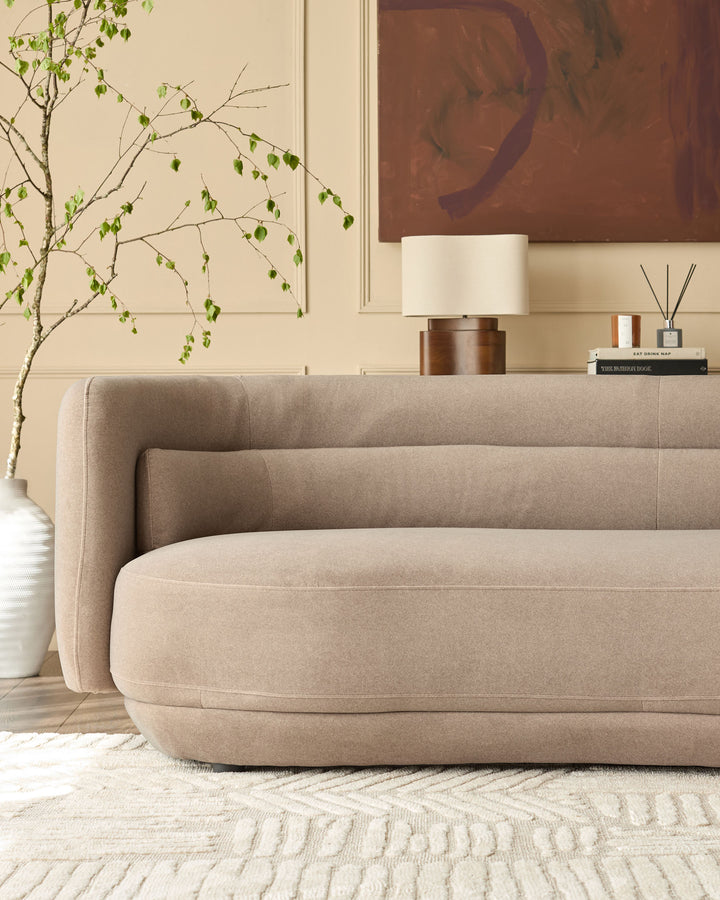 Henry 3-seater sofa in mocha fabric with curved, rounded arms and base, displayed in a styled living room setting.