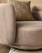 Henry Swivel Love Seat in mocha fabric with patterned throw pillow, rounded arms, and curved seat base.
