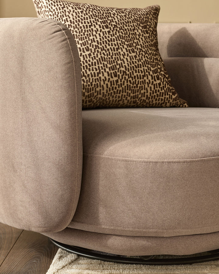 Henry Swivel Love Seat in mocha fabric with patterned throw pillow, rounded arms, and curved seat base.