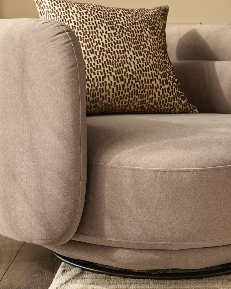 Henry Swivel Love Seat in mocha fabric with patterned throw pillow, rounded arms, and curved seat base.