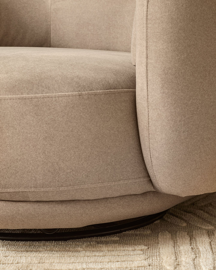 Henry swivel love seat in mocha fabric, close-up of curved armrest and base detail on neutral rug.