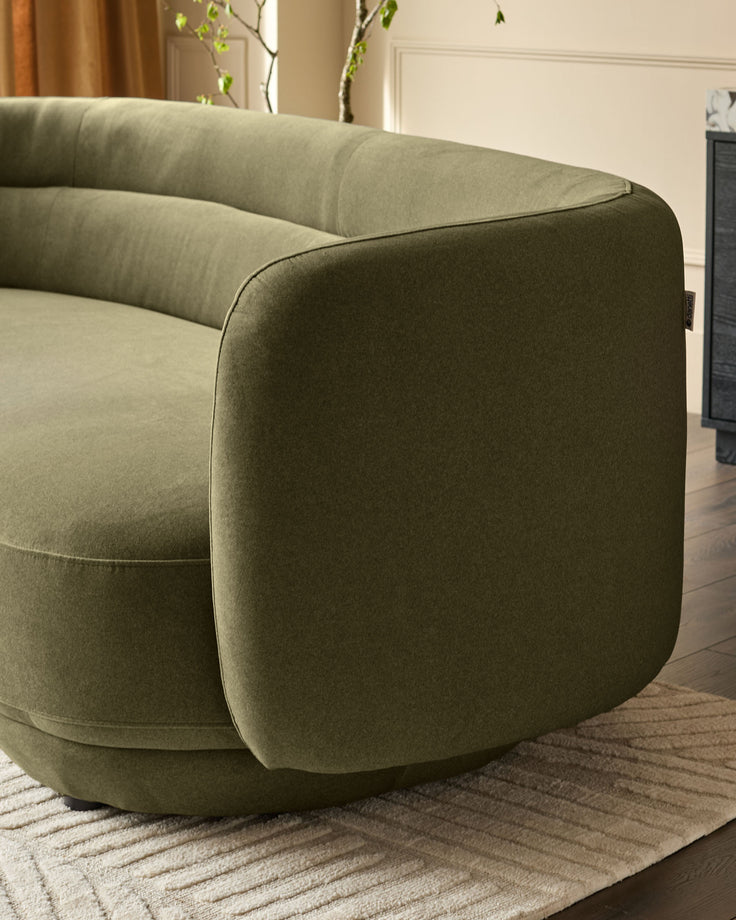 Henry 3-seater sofa in olive green velvet, curved armrest detail, side view on neutral rug.