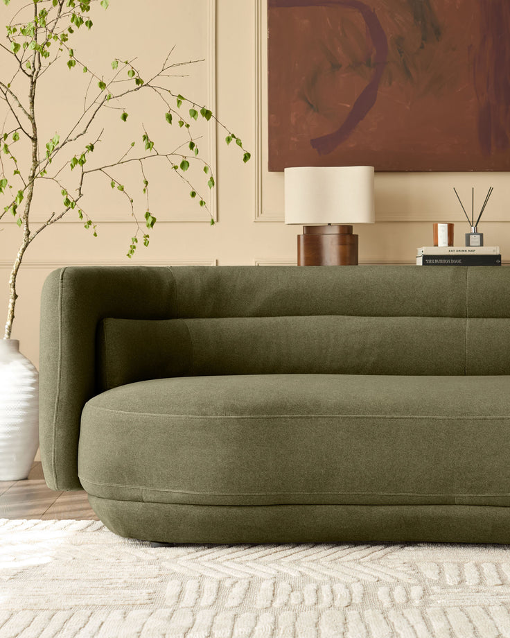 Henry 3-seater sofa in olive green velvet, curved design, shown in styled living room setting.