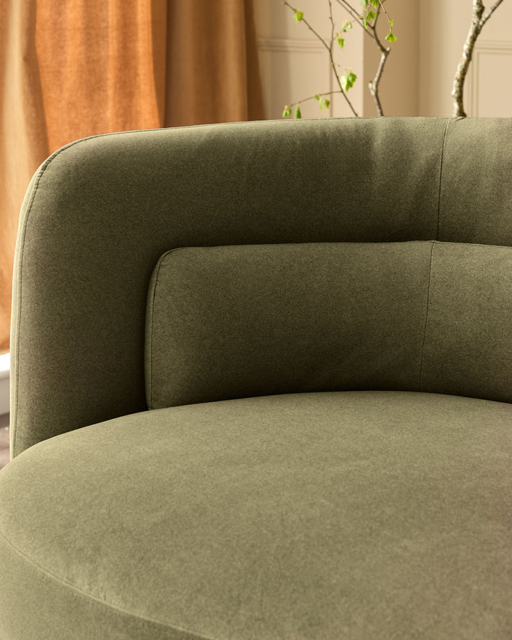 Henry 3-seater sofa in olive green velvet, curved design with rounded backrest, shown from side angle in styled room setting.