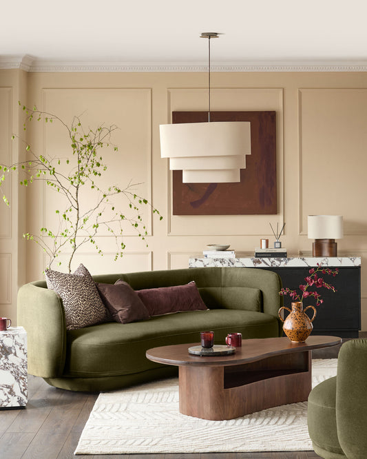 Henry three-seater sofa in olive green velvet, curved design, positioned in a cream and brown living room setting.