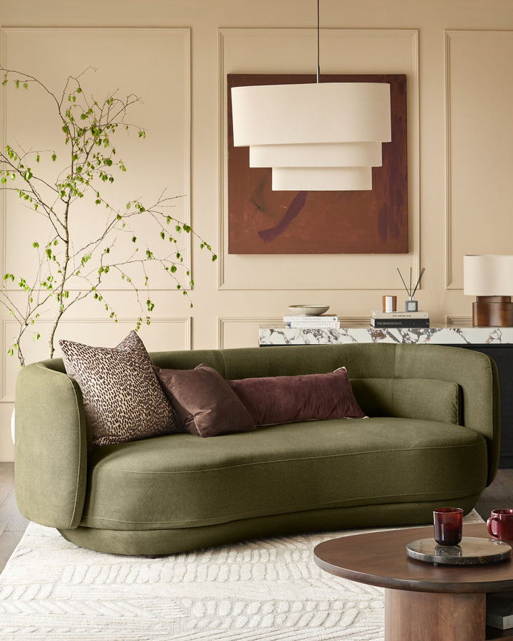 Henry 3-seater sofa in olive green velvet with curved arms, styled with burgundy pillows in a neutral living room.