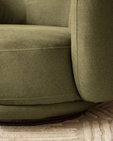 Henry swivel love seat in olive green velvet, showing curved armrest and seating detail on neutral rug.