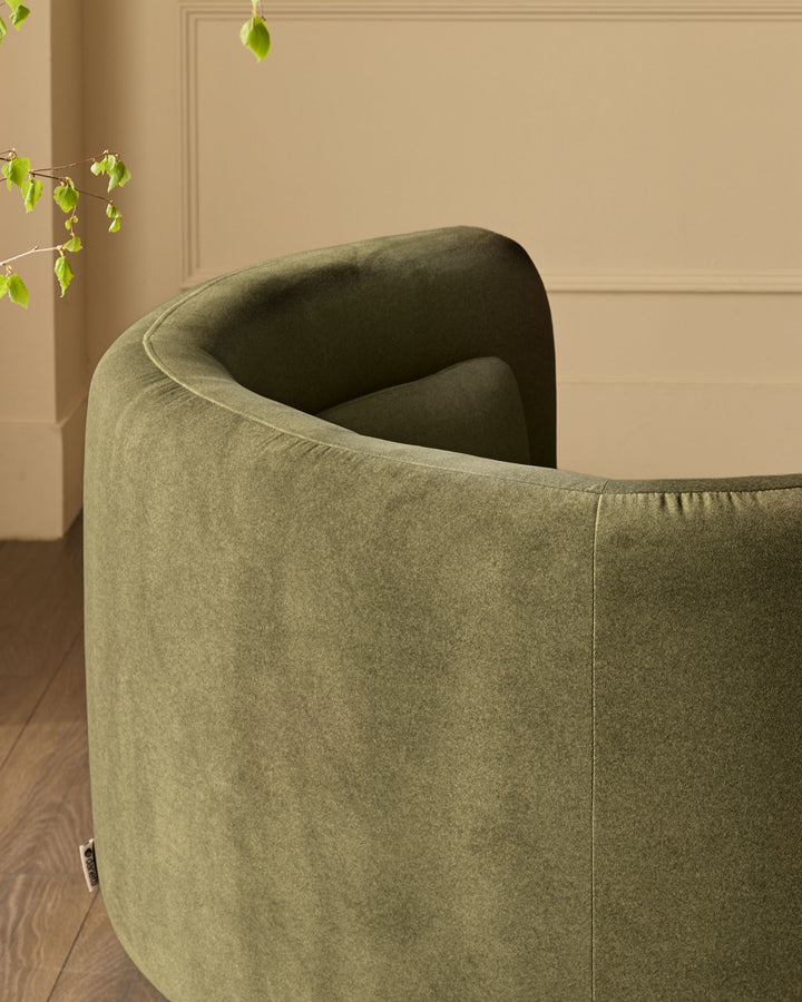Henry Swivel Love Seat in olive green velvet, shown from rear angle highlighting curved back and upholstered design.