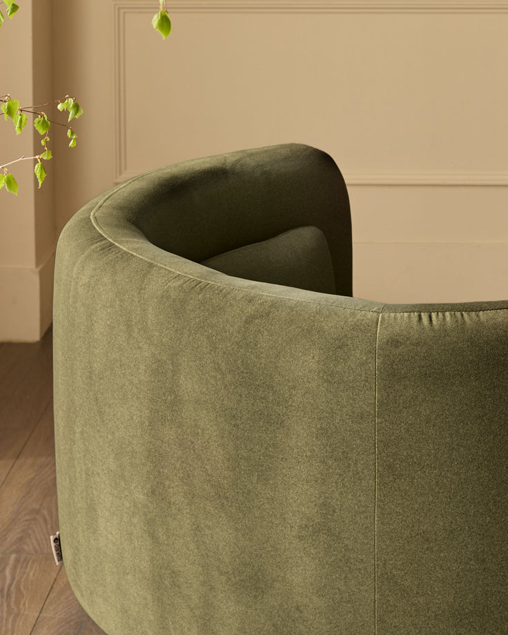Henry Swivel Love Seat in olive green velvet, shown from rear angle highlighting curved back and upholstered design.