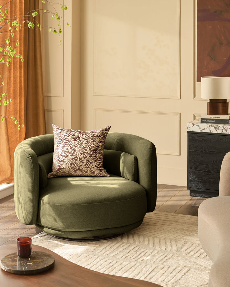 Henry swivel love seat in olive green velvet, shown in a styled living room setting with decorative pillow.