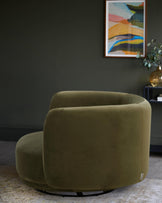 Olive green swivel chair with artwork and a plant, creating a stylish and inviting interior setting.