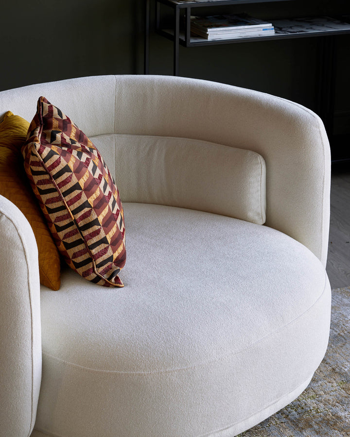 Stylish cream coloured armchair with patterned cushions in a contemporary setting. Perfect for modern living rooms.