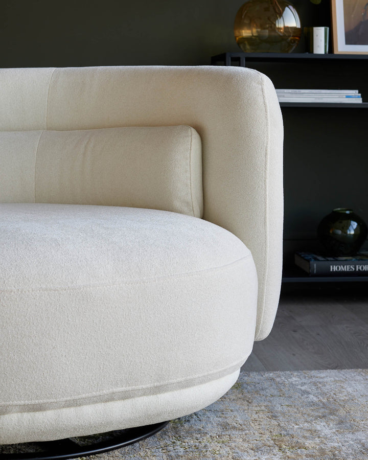 Close-up of a contemporary cream swivel chair with a rounded seat and backrest, positioned on a patterned rug.